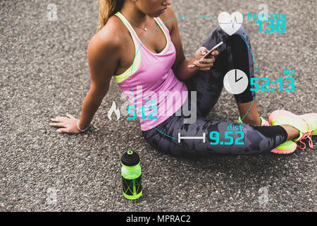 Sportive young woman having a break with data emerging from smartphone Stock Photo