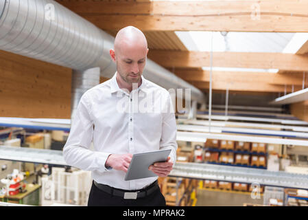 Businessman using tablet in modern factory Stock Photo