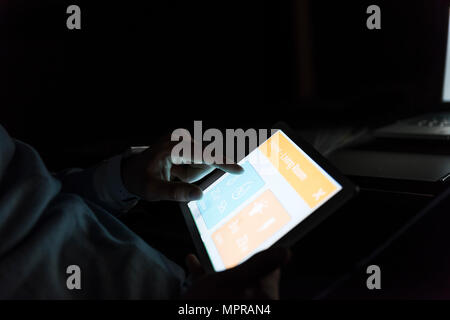 Businessman working on tablet at dark, close-up Stock Photo