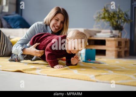 Mother and son playing at home, baby learning to crawl Stock Photo