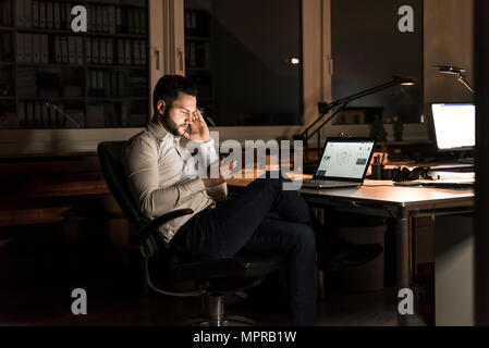 Businessman using tablet in office at night Stock Photo