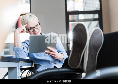 Smiling woman using tablet in office Stock Photo