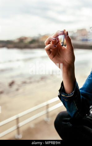 Hand of a woman smoking a cigarette in a coastal village Stock Photo
