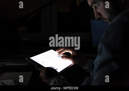 Businessman working on tablet in the dark, close-up Stock Photo