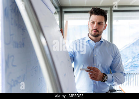 Businessmen standing at flipchart in office Stock Photo