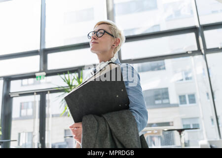 Smiling woman in office building carrying file folder Stock Photo