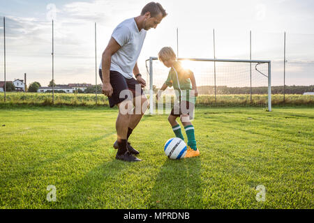 Coach and young football player on football ground at sunset Stock Photo