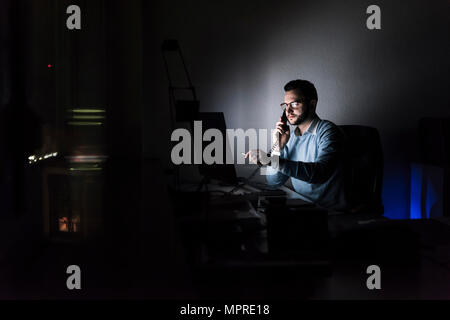 Businessman on the phone in office at night Stock Photo