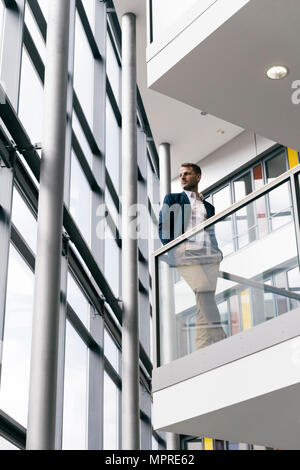 Businessman in office building looking out of window Stock Photo