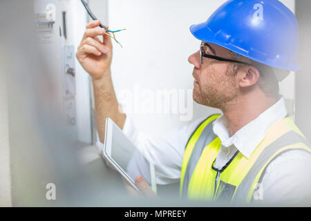 Electrician inspecting wire at fusebox Stock Photo