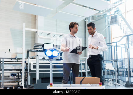 Two men with clipboard talking on factory shop floor Stock Photo - Alamy