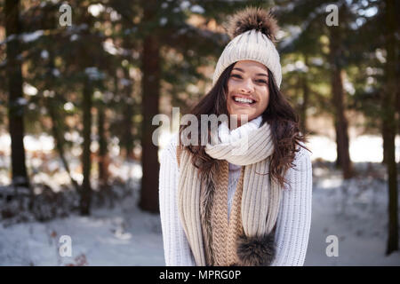 Portrait of laughing young woman wearing knitwear in winter forest Stock Photo