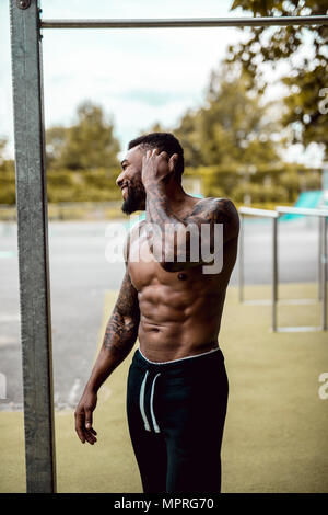 Tattooed bodybuilder standing on sports field Stock Photo