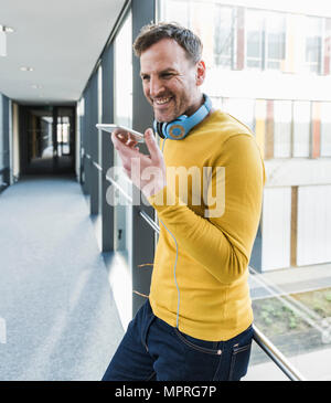 Casual smiling businessman in office using smartphone Stock Photo