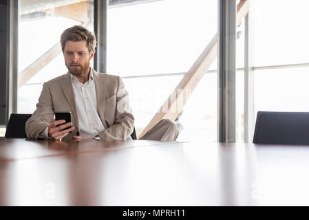 Businessman using cell phone in conference room Stock Photo