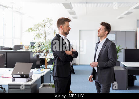 Two businessmen standing in office, discussing solutions Stock Photo