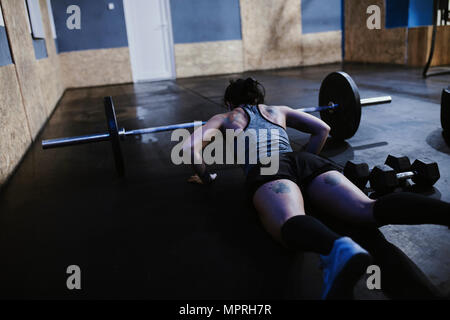 Woman doing push ups at barbell in gym Stock Photo