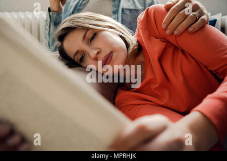 Happy couple reading and cuddling at home Stock Photo