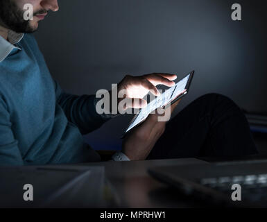 Businessman working on tablet in office at night, close-up Stock Photo