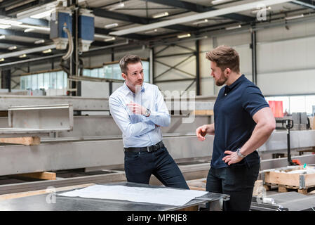 Two men talking on factory shop floor Stock Photo