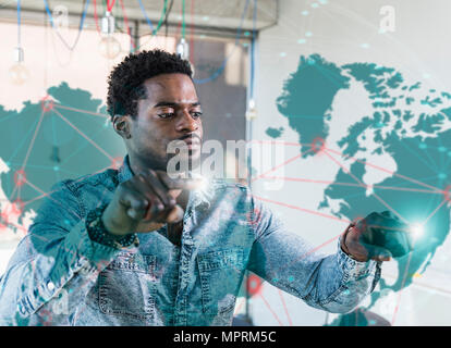 Casual businessman touching glass pane with world map in office Stock Photo
