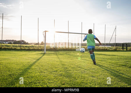 Young football player on football ground at sunset Stock Photo