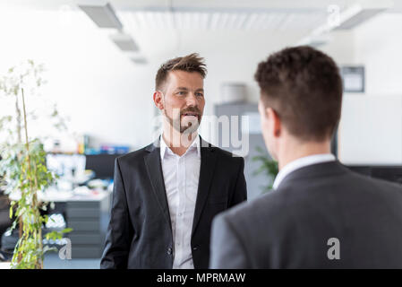 Two businessmen standing in office, discussing solutions Stock Photo