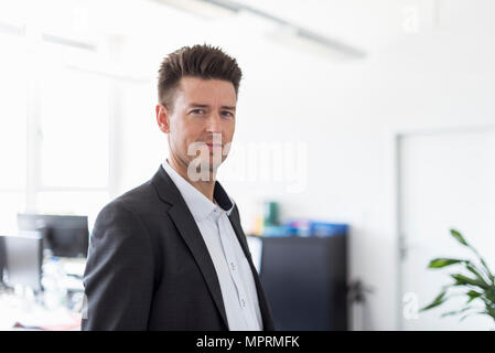 Portrait of a successful businessman standing in office, looking serious Stock Photo