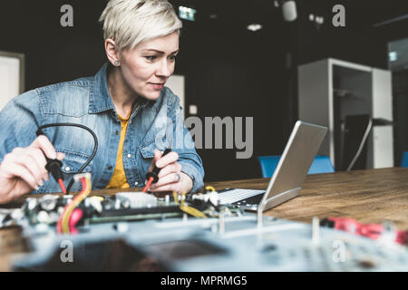 Woman working on computer equipment looking at laptop Stock Photo