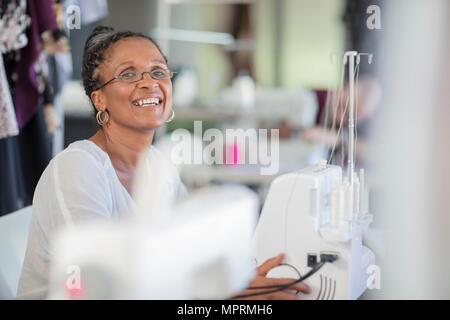 Portrait of happy seamstress with sewing machine Stock Photo