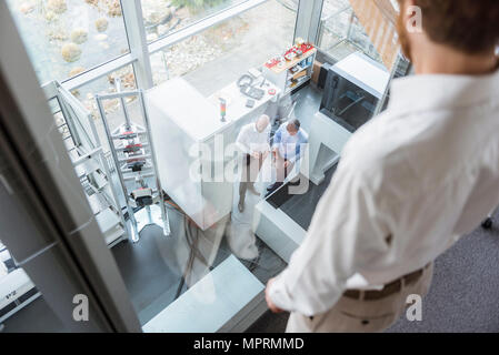 Businessman watching colleagues talking in industrial office Stock Photo