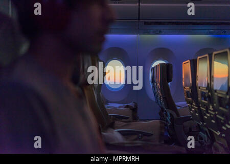 Young man in plane wearing headphones Stock Photo