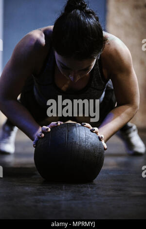Woman doing push ups on ball in gym Stock Photo