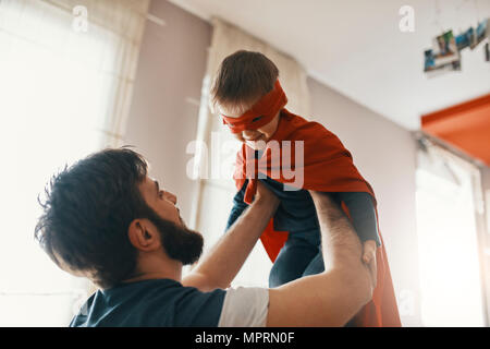 Father playing with his little son dressed up as a superhero Stock Photo