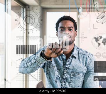 Casual businessman touching glass pane with data in office Stock Photo