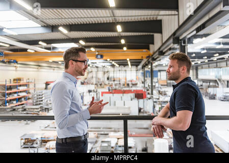Two men talking on factory shop floor Stock Photo