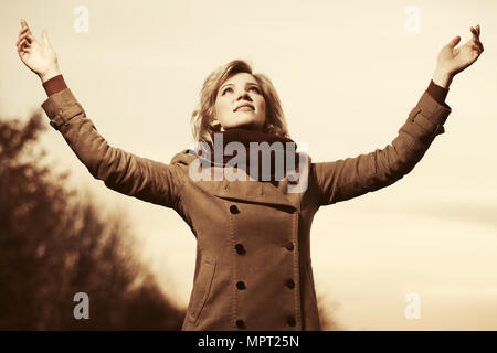 Happy young fashion woman raising her hands in the sky Stock Photo