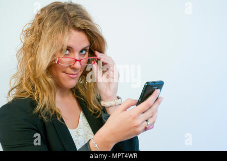 Young businesswoman, wearing spectacles, using mobile phone. Stock Photo