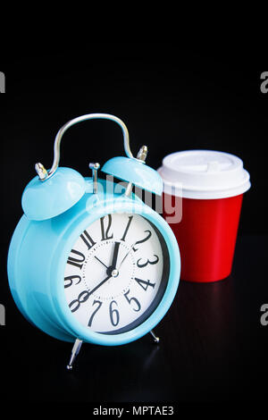 Blue alarm clock and paper cup on black background Stock Photo