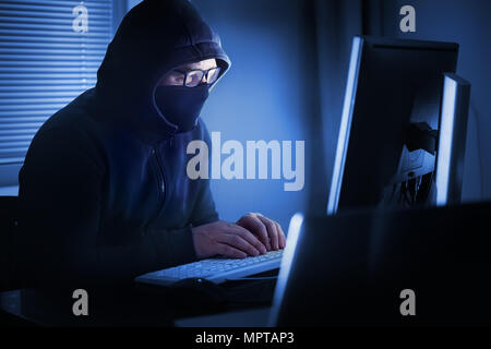 Hacker in front of his computer. Dark face Stock Photo
