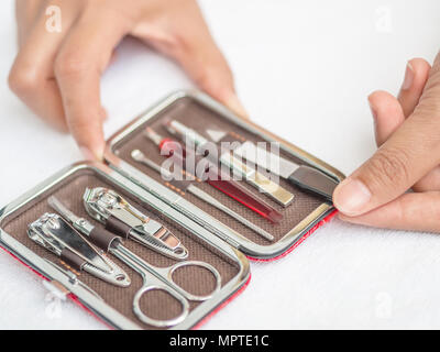 Closeup woman hand holding traveler's nail care kit of necessary tools set including scissors, tweezers, nail file and trimmer in red leather pocket c Stock Photo