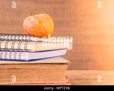 Back to school concept. Retro style of apple on stacks of books on  wooden table background. Stock Photo