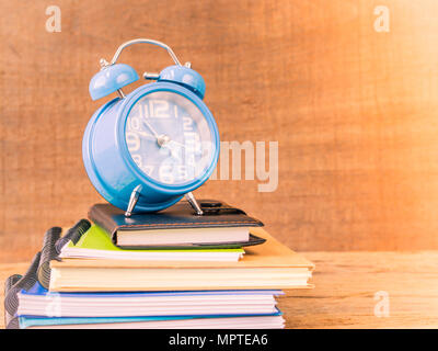 Back to school concept. Retro style of alarm clock on stacks of books with  wooden table background. Stock Photo