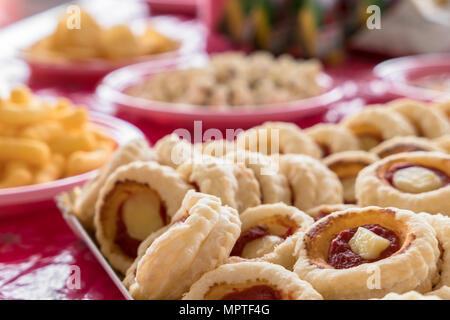 Close-up to mini pizzas and on blurry background, fries chips and popcorn. Food for parties, birthdays and holidays. Defocused blurry background. Stock Photo