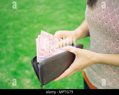 Closeup woman hand putting money into leather wallet . Business and financial, money saving concept. Stock Photo