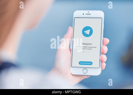 Telegram messenger on Apple iPhone in woman hands over the shoulder view. Stock Photo