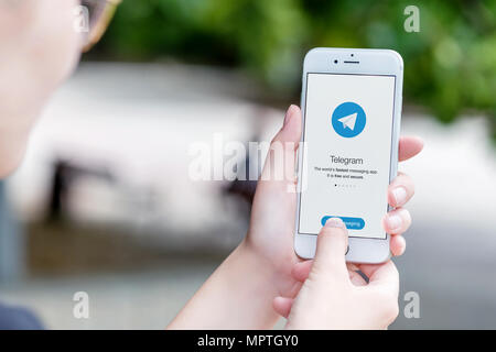 Telegram messenger on Apple iPhone in female hands over the shoulder view. Stock Photo