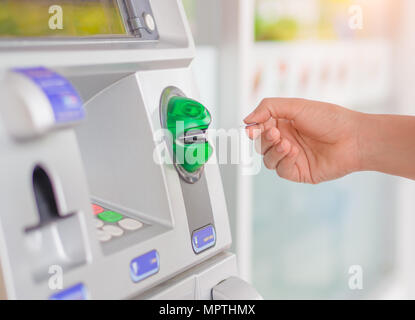 Close-up of woman's hand inserting debit card into an ATM machine. Stock Photo