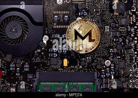 A Monero physical coin sitting on a computer motherboard with a fan and RAM.  open-source cryptocurrency created in April 2014 that focuses on privacy. Stock Photo