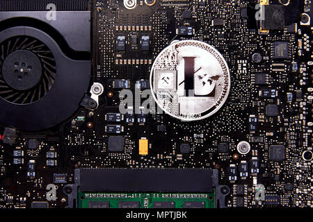 An Litecoin physical coin sitting on a computer motherboard with a fan and RAM. Litecoin is a peer-to-peer cryptocurrency and open source software. Stock Photo